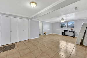 Interior space with ornamental molding, light tile patterned floors, a textured ceiling, and ceiling fan