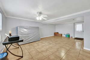 Living area featuring crown molding, ceiling fan, a textured ceiling, and light tile patterned floors