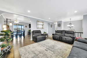 Living room with ornamental molding, ceiling fan with notable chandelier, a textured ceiling, and light hardwood / wood-style flooring