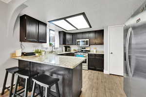 Kitchen with light hardwood / wood-style floors, sink, stainless steel appliances, and kitchen peninsula