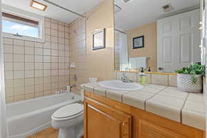 Full bathroom with shower / bathtub combination with curtain, vanity, toilet, and tile patterned floors