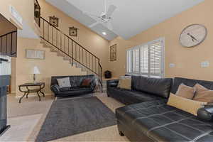 Carpeted living room featuring high vaulted ceiling and ceiling fan