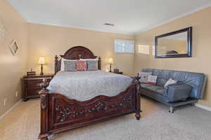 Bedroom with ornamental molding and light carpet