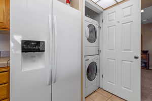 Clothes washing area featuring stacked washer / dryer and light tile patterned floors