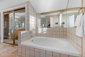 Bathroom with tiled tub and tile patterned floors