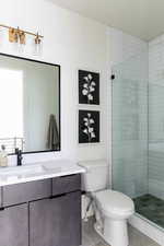 Bathroom with vanity, tile patterned flooring, toilet, and tiled shower