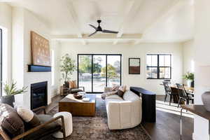 Living room featuring beam ceiling, a healthy amount of sunlight, a fireplace, and dark hardwood / wood-style flooring