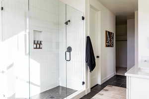 Bathroom featuring vanity, tile patterned flooring, and a shower with door