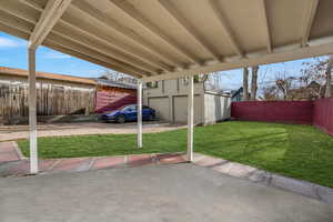 View of patio featuring a shed with grass edited to look greener