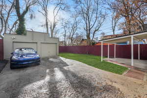 Garage featuring a carport and a yard with grass edited to look greener