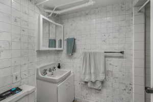 Bathroom featuring vanity, tile walls, walk in shower, and toilet