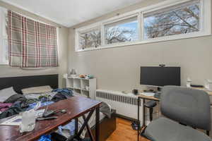 Home office with radiator heating unit and light wood-type flooring