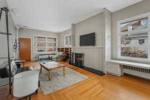 Living room featuring a fireplace, radiator, and a wealth of natural light