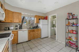 Kitchen with tasteful backsplash, light tile patterned flooring, sink, and white appliances