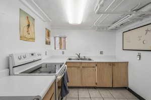 Kitchen featuring sink, light tile patterned floors, and electric range