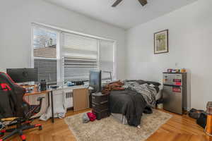 Bedroom with stainless steel fridge, light parquet flooring, and ceiling fan