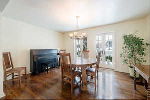 Dining space featuring dark wood-type flooring, a chandelier, and french doors