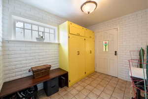 Interior space with light tile patterned flooring and brick wall