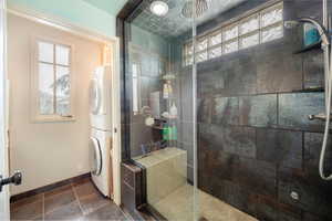 Bathroom featuring a tile shower, tile patterned floors, and stacked washer / dryer