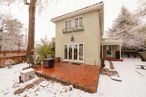 Snow covered rear of property with a balcony and a patio area