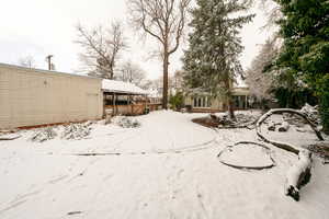 Yard layered in snow featuring a hot tub