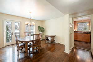 Dining space with sink, a notable chandelier, dark hardwood / wood-style flooring, and french doors