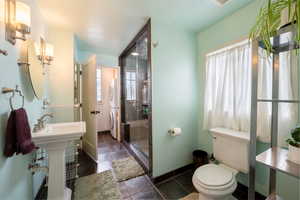 Bathroom with tile patterned flooring, walk in shower, sink, and toilet