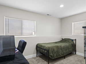 Bedroom featuring light carpet and multiple windows