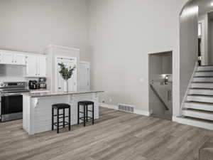 Kitchen featuring white cabinetry, a center island, electric range, and a kitchen breakfast bar