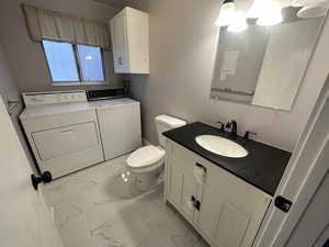 Bathroom featuring vanity, washer and clothes dryer, and toilet