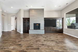 Unfurnished living room featuring dark hardwood / wood-style floors and a large fireplace