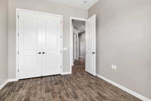 Unfurnished bedroom featuring dark wood-type flooring and a closet