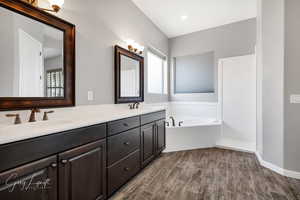 Bathroom with vanity, a tub to relax in, and wood-type flooring