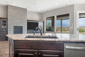 Kitchen featuring sink, dark brown cabinets, light stone counters, light hardwood / wood-style floors, and stainless steel dishwasher