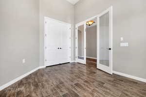 Unfurnished bedroom featuring a closet, dark hardwood / wood-style flooring, and french doors