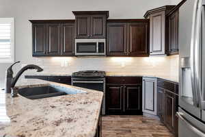 Kitchen featuring dark brown cabinetry, stainless steel appliances, sink, and backsplash