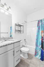 Full bathroom with shower / bathtub combination with curtain, vanity, tile patterned flooring, and toilet