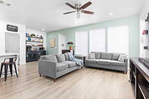 Living room featuring ceiling fan, bar, and light hardwood / wood-style floors