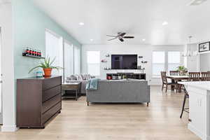 Living room featuring ceiling fan with notable chandelier, light hardwood / wood-style floors, and a textured ceiling