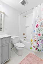 Full bathroom featuring vanity, a textured ceiling, shower / bath combination with curtain, and toilet