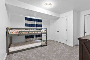 Bedroom with light colored carpet and a textured ceiling