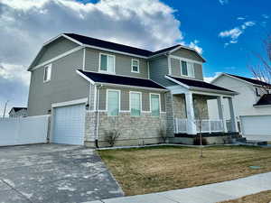 View of front of home featuring a garage, a porch, and a front lawn