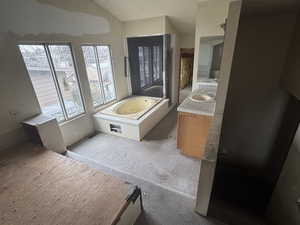 Bathroom featuring sink, vaulted ceiling, and a tub