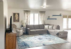 Living room with ornamental molding, wood-type flooring, and french doors