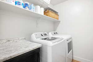 Washroom with wood-type flooring and washing machine and dryer