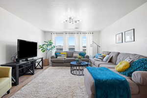 Living room featuring a notable chandelier, a textured ceiling, and light hardwood / wood-style floors