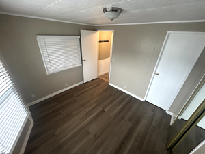 Unfurnished bedroom featuring ornamental molding, dark hardwood / wood-style floors, and a textured ceiling