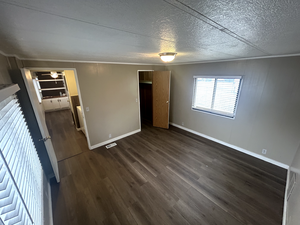 Unfurnished bedroom featuring crown molding, dark hardwood / wood-style floors, and a textured ceiling