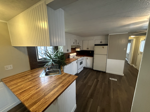 Kitchen with dark hardwood / wood-style floors, sink, white cabinets, wooden counters, and white appliances