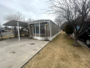 View of side of home with a carport and a lawn